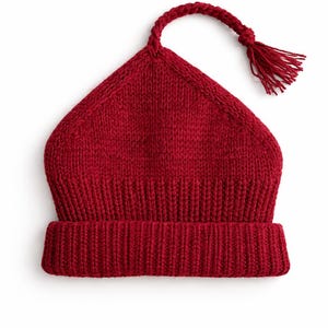 Puede incluir: Un gorro rojo tejido con una forma triangular única y un cordón trenzado con borla. El gorro tiene un borde acanalado y está hecho de un material suave y cálido. Un elegante accesorio de invierno.
