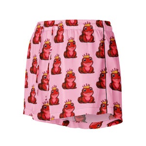 Puede incluir: Pantalones cortos de pijama rosas con un estampado repetido de ranas rojas con coronas doradas. Los pantalones cortos tienen cintura con cordón y ribete negro. Un diseño divertido para ropa de dormir.