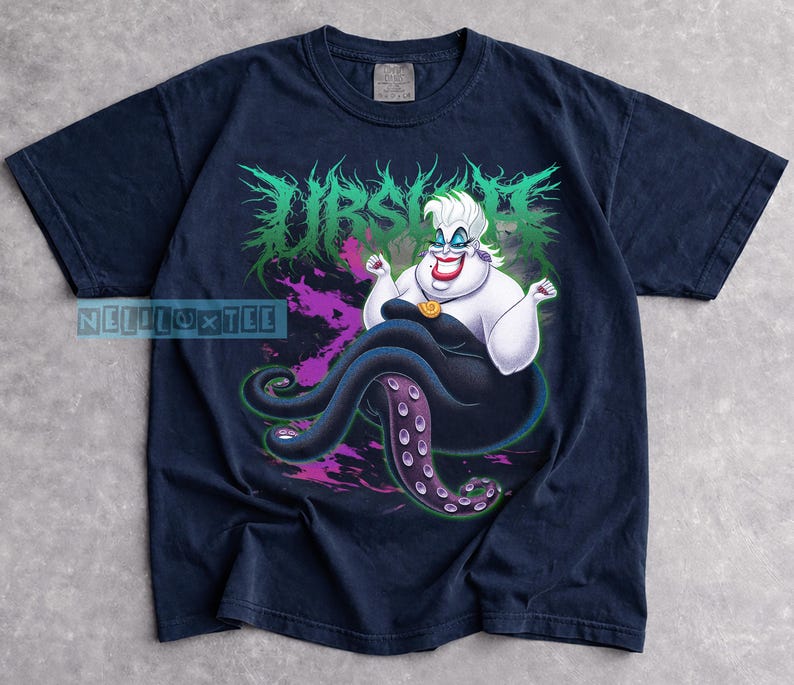 May include: Navy blue t-shirt featuring a graphic of Ursula from The Little Mermaid. The design includes Ursula with her tentacles, the word "Ursula" in green, and purple accents. The shirt is a comfortable, casual wear.