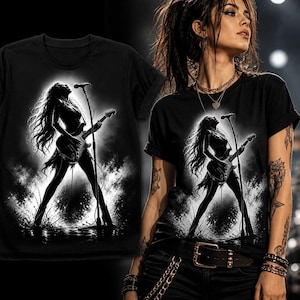 May include: Black t-shirt with a monochrome graphic of a female guitarist playing on stage. The design includes a microphone and guitar, set against a smoky backdrop. The t-shirt is a classic crew neck style.