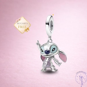 May include: A silver charm featuring the character Stitch from Lilo & Stitch, with blue eyes, pink ears, and a purple design on its chest. The charm is suspended from a silver loop. The image also includes the text "BUY 2 GET 1 FREE".