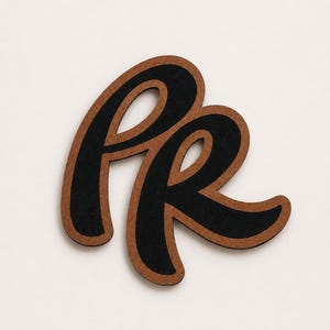 May include: A decorative wooden letter "R" in a cursive font. The letter is black with a brown border. The design is simple and elegant, suitable for home decor or craft projects.