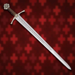 Può includere: Una spada in metallo color argento con impugnatura rivestita in pelle marrone, guardia a croce e pomolo circolare. La lama è incisa con il testo latino "NON NOBIS DOMINE NON NOBIS SED NOMINI TUO DA GLORIAM" lungo il suo sguscio centrale.