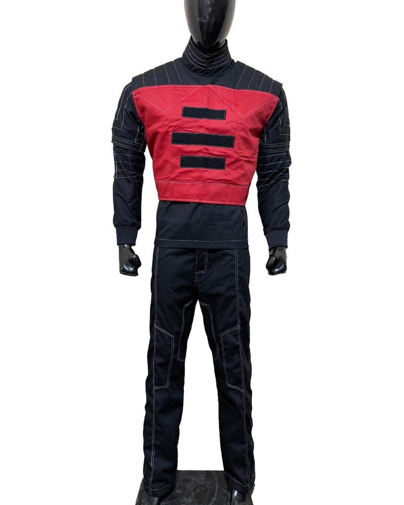 May include: A black and red outfit with white stitching. The outfit includes a black turtleneck, long-sleeved shirt, and pants. A red vest with three black horizontal stripes is worn over the shirt. The pants have white stitching.