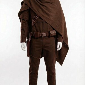 May include: A brown costume displayed on a mannequin. The outfit includes a long-sleeved shirt, pants, a belt with pouches, a holster, and a cape. The boots are brown. The costume is a complete ensemble.