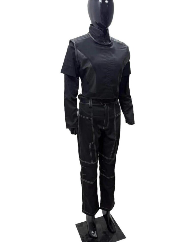 Puede incluir: Traje negro sobre un maniqu&iacute;. El traje incluye una parte superior de manga larga con cuello alto y un pantal&oacute;n. El pantal&oacute;n y la parte superior tienen costuras blancas. El maniqu&iacute; est&aacute; sobre una base negra.