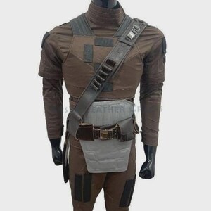 Puede incluir: Traje t&aacute;ctico marr&oacute;n con peto, bandolera y cintur&oacute;n. El atuendo incluye una camisa de manga larga, pantalones y guantes. El disfraz tiene m&uacute;ltiples bolsillos y un protector gris para la parte inferior del torso.