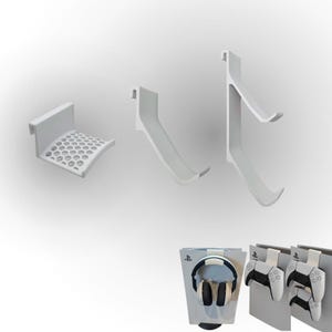 May include: A set of white plastic gaming accessory mounts including a honeycomb-patterned headset holder and two controller hooks. The mounts are designed to hang over the edge of a console, as shown with a headset and two game controllers.