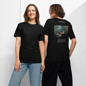 May include: A black short-sleeved t-shirt featuring a graphic on the back. The graphic includes the text "INNOVATE & INSPIRE" above a rectangular image of a workspace and a paragraph of small, illegible white text printed on the black fabric.
