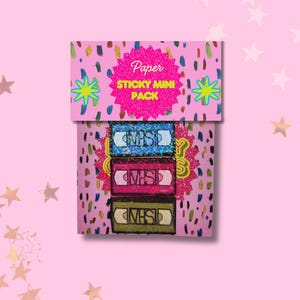 May include: A pink paper sticky mini pack featuring three colorful VHS tape designs. The pack has a pink glittery top with the words "Paper STICKY MINI PACK" and star and dot accents. The VHS tapes are blue, pink, and green.