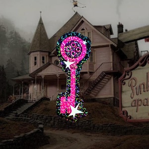 May include: A pink key-shaped decoration with a glittery, multi-colored outline and white star accents. The key is set against a backdrop of a pink house with a dark, overcast sky and a sign that reads "Pink apa".