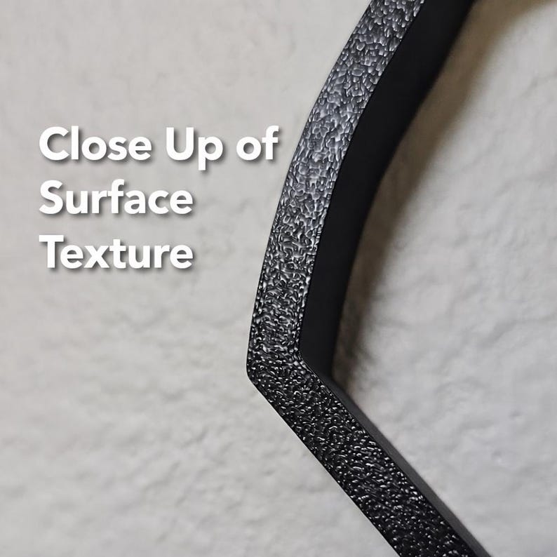 May include: A black, angular object with a rough, granular, and textured surface. The text 'Close Up of Surface Texture' is printed in white on the left side of the image, providing a clear view of the material's finish and physical detail.