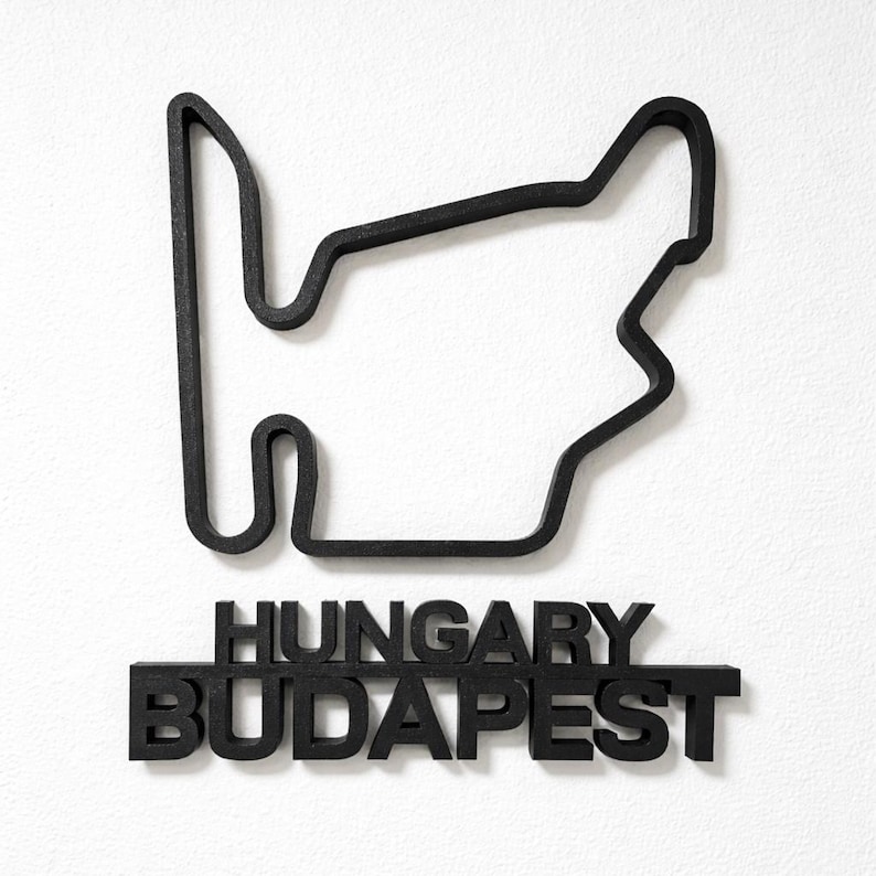 May include: A black wall-mounted sculpture depicting the Hungaroring race track outline. Below the track shape, the words HUNGARY and BUDAPEST are displayed in bold, black, capital letters. The entire piece is constructed from a solid material.