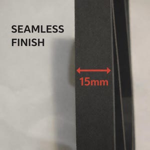 May include: A black, flat, rectangular strip with a matte texture. The text SEAMLESS FINISH is printed in black on the left. A red horizontal arrow indicates a width of 15mm across the black strip, highlighting its specific measurement.