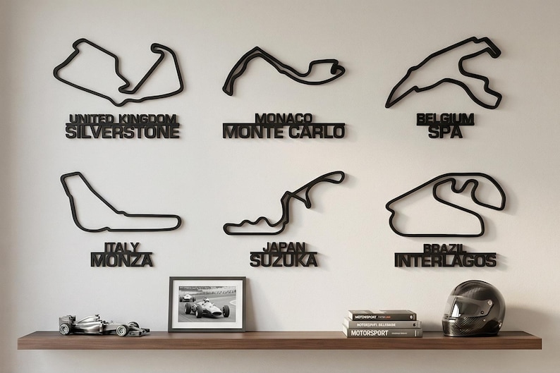 May include: Six black wall-mounted outlines of Formula 1 race tracks including Silverstone, Monte Carlo, Spa, Monza, Suzuka, and Interlagos. Below the tracks, a shelf holds a small framed photograph of a race car, three books, and a helmet.