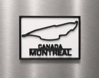 Può includere: Una targa rettangolare da parete con il profilo nero stampato in 3D del circuito del Gran Premio di Montreal in Canada. Sotto il tracciato, il testo CANADA MONTREAL è riportato in lettere nere, spesse e in rilievo su sfondo bianco.