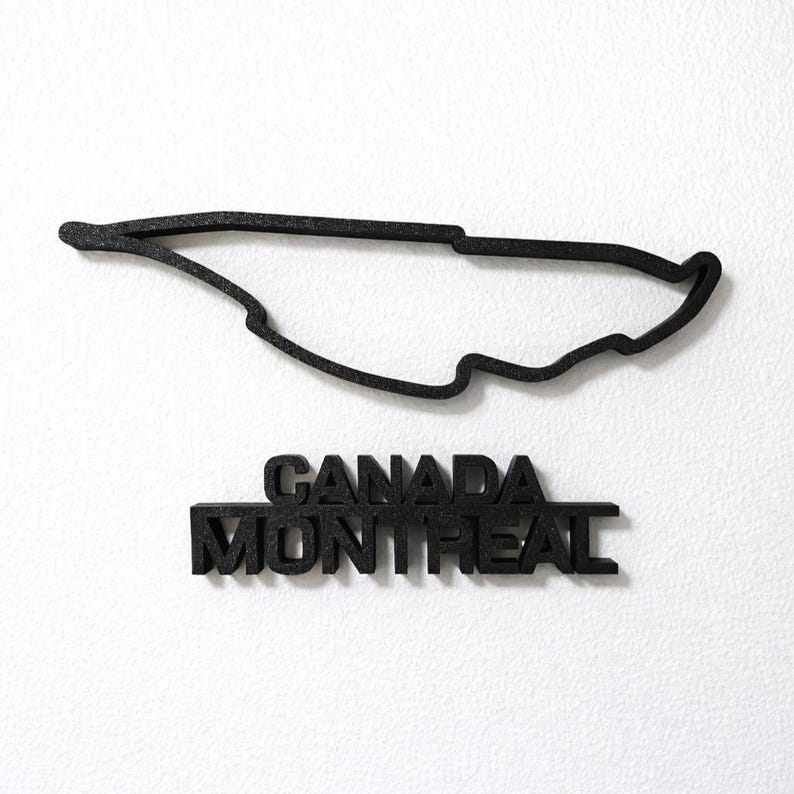 May include: A black, three-dimensional outline of the Circuit Gilles Villeneuve racetrack in Montreal, Canada. Below the track layout, the words CANADA and MONTREAL are displayed in bold, black, block-style capital letters.