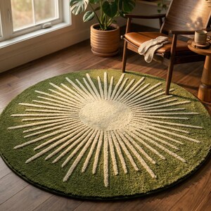 Top-down view of a round olive green hand-tufted wool rug featuring a cream cut and loop pile sunburst pattern in a sunlit boho living room.