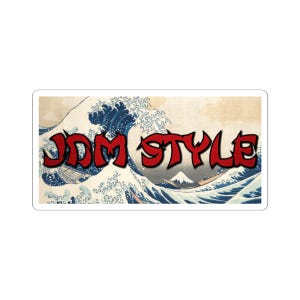 May include: Rectangular sticker with the text "JDM STYLE" in red with a black outline. The background shows a classic Japanese wave illustration in blue, white, and beige, with a mountain in the distance.