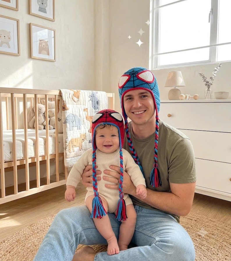 Puede incluir: Dos gorros de ganchillo a juego con un dise&ntilde;o en azul y rojo, detalles de telara&ntilde;a en negro y grandes parches blancos para los ojos. Cada gorro incluye largas orejeras trenzadas que terminan en borlas de colores, imitando una m&aacute;scara.