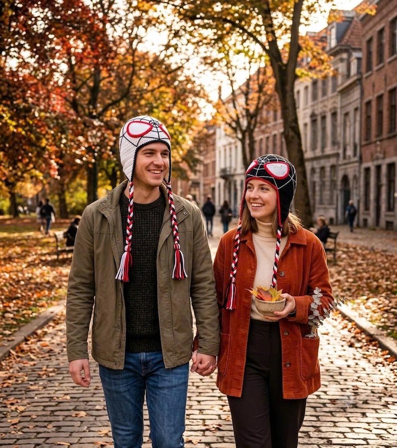 Puede incluir: Dos gorros de punto con patr&oacute;n de telara&ntilde;a y parches grandes en forma de ojos. Un gorro es blanco con l&iacute;neas negras y detalles rojos, el otro es negro con l&iacute;neas rojas y detalles blancos, ambos incluyen largas orejeras trenzadas con borlas.