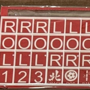 May include: A red and white tile set with letters, numbers, and symbols. The tiles spell out "RRR LLL OOOOO LLL RRR 123". Additional symbols and text are visible at the bottom of the set.