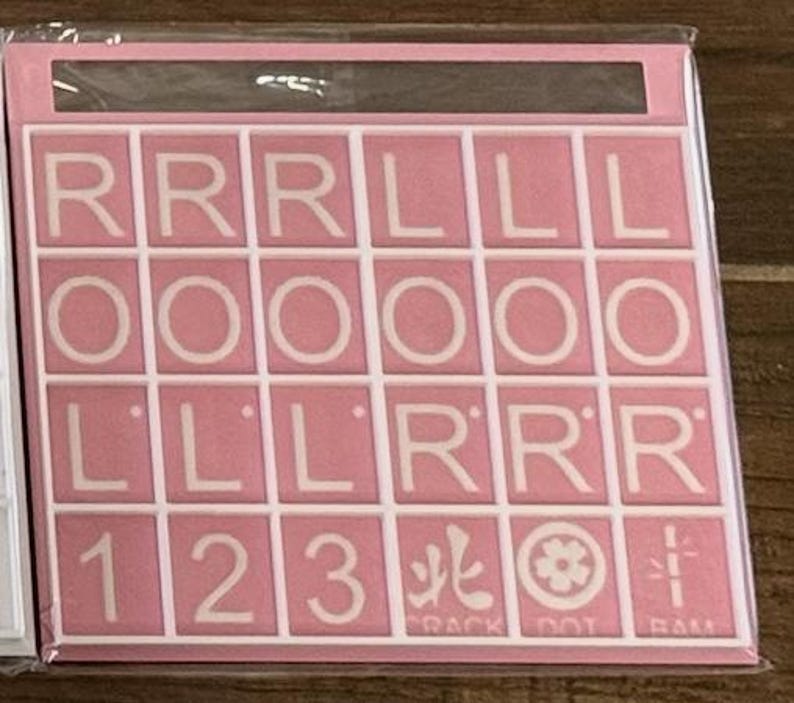 May include: A pink Scrabble tile set with white letters and numbers. The tiles include the letters R, L, and O, along with the numbers 1, 2, and 3. The set also includes symbols and the text "CRACK DOT RAM".