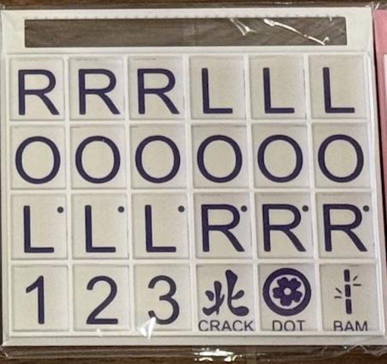 May include: A set of white tiles with dark blue letters and symbols. The tiles include the letters R, L, and O, along with the numbers 1, 2, and 3. The set also features the words CRACK, DOT, and BAM.