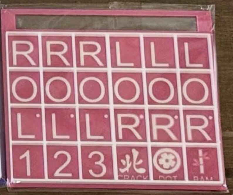 May include: Pink and white tile set with letters, numbers, and symbols. The tiles are arranged in a grid, with the letters spelling out "RRRLLLOOOOLLLLRRR" and numbers 1, 2, and 3. The bottom row has symbols and the words "CRACK DOT DAM".