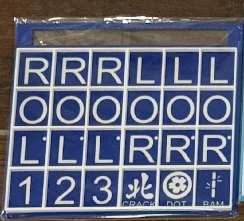 May include: A blue and white letter and number tile set. The tiles are arranged in a grid, with letters and numbers. The bottom row includes the numbers 1, 2, and 3, along with three symbols and the words "CRACK", "DOT", and "RAM".