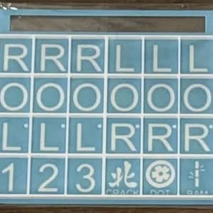 May include: A light blue Scrabble tile set with white letters and numbers. The tiles spell out words and include the numbers 1, 2, and 3. The bottom row includes the words "CRACK", "DOT", and "DAM".