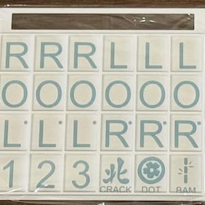 May include: A set of white tiles with light blue letters and symbols. The tiles include the letters R, L, and O, along with the numbers 1, 2, and 3. The words CRACK, DOT, and BAM are also present.