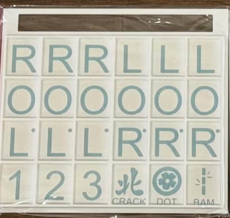 May include: A set of white tiles with light blue letters and symbols. The tiles include the letters R, L, and O, along with the numbers 1, 2, and 3. The words CRACK, DOT, and BAM are also present.