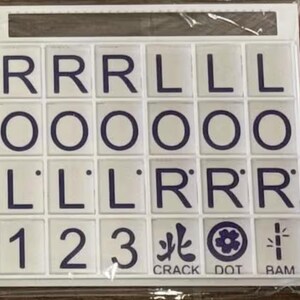 May include: A set of white tiles with dark blue letters and symbols. The tiles display letters R, L, and O, along with numbers 1, 2, and 3. The words "CRACK", "DOT", and "BAM" are also present.