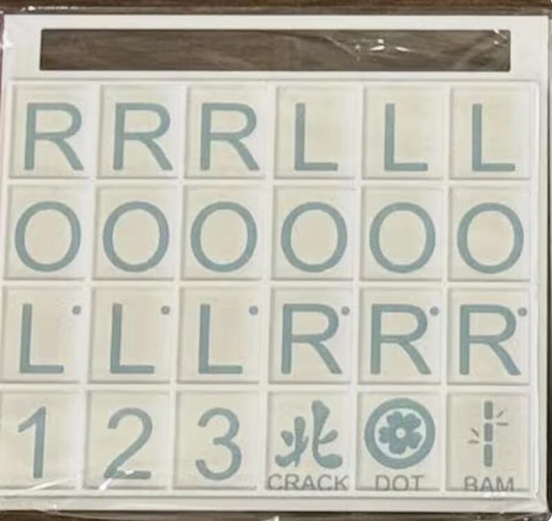 May include: A white tile game board with light blue letters and numbers. The tiles spell out letters and numbers, with the words "CRACK", "DOT", and "BAM" at the bottom. The game board is in a white frame.