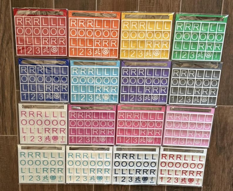 May include: A collection of colorful Scrabble tile sets in various colors, including red, orange, yellow, green, blue, purple, white, pink, and black. Each set contains letter tiles and number tiles, perfect for word games.