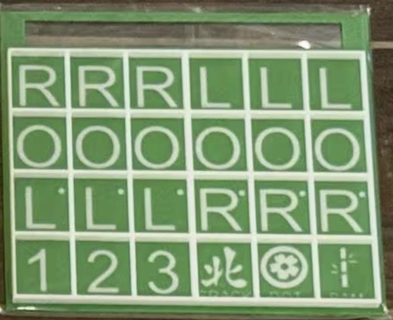 May include: A green and white game board with a grid of squares containing letters, numbers, and symbols. The letters include R, L, and O. Numbers 1, 2, and 3 are also present. The board is in a green frame.