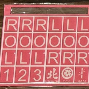 May include: A pink game board with white letter and number tiles. The tiles spell out letters and numbers, including the numbers 1, 2, and 3. The bottom row includes the words "CRACK", "DOT", and "RAM".