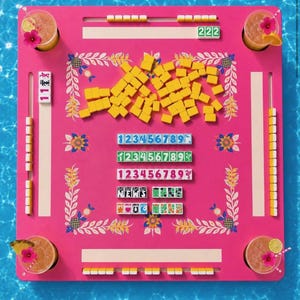Może przedstawiać: Żywy r&oacute;żowy zestaw do gry w Mahjong z ż&oacute;łtymi kafelkami i kwiatowymi akcentami. Zestaw zawiera kafelki z numerami, kości i cztery koktajle z kwiatowymi dodatkami. Gra jest ustawiona na tle niebieskiej wody.