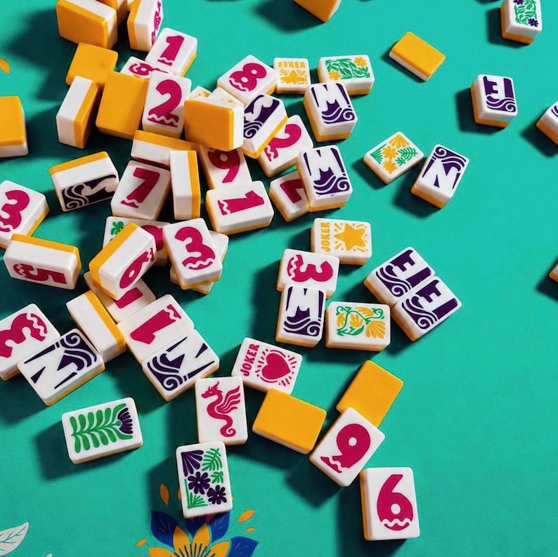 May include: A collection of Mahjong tiles scattered on a teal surface. The tiles are white with red numbers and symbols, and some have yellow or purple accents. Several tiles are marked with the word "Joker".