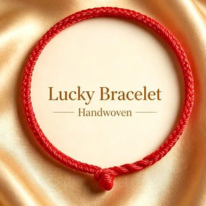 May include: A circular red handwoven cord bracelet featuring a knot at the bottom. The center of the bracelet displays the text Lucky Bracelet Handwoven in dark brown lettering against a light cream-colored circular background.