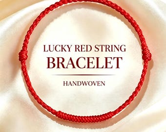Puede incluir: Una pulsera fina de hilo rojo tejida a mano con dos pequeños nudos en los laterales y una sección trenzada más gruesa en la parte inferior. El texto LUCKY RED STRING BRACELET y MAY ALL YOUR WISHES COME TRUE aparece en rojo oscuro.