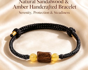 Puede incluir: Una pulsera de cordón negro con una cuenta rectangular de madera marrón en el centro, flanqueada por dos cuentas redondas de ámbar amarillo. El texto Natural Sandalwood & Amber Handcrafted Bracelet Serenity, Protection & Steadiness aparece arriba.