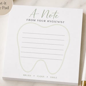 May include: A square 4-inch by 4-inch white note pad featuring a light green tooth outline with horizontal lines for writing. The text reads A Note FROM YOUR HYGIENIST at the top and BRUSH • FLOSS • SMILE at the bottom. A white pen is placed beside it.