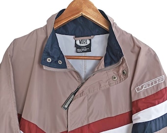 May include: A beige, blue, red, and white striped jacket with a zipper closure and a Vans logo on the right sleeve.