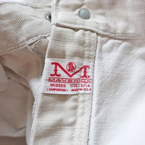 K&ouml;nnte beinhalten: Eine wei&szlig;e Jeans mit einem roten Etikett mit der Aufschrift "Maverick Misses Size 5/16 Sanforized Made in U.S.A."