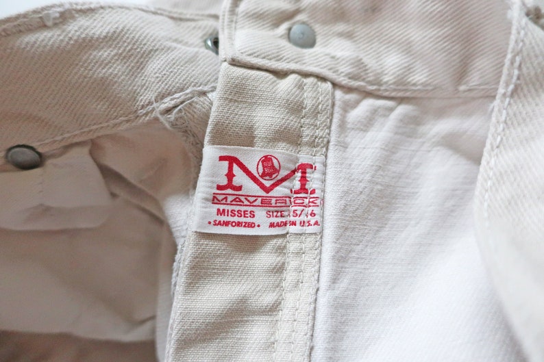 K&ouml;nnte beinhalten: Eine wei&szlig;e Jeans mit einem roten Etikett mit der Aufschrift "Maverick Misses Size 5/16 Sanforized Made in U.S.A."