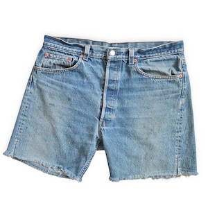 May include: A pair of light blue denim shorts with frayed edges. The shorts have five pockets, a button fly, and a belt loop waistband.