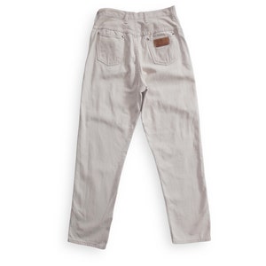 K&ouml;nnte beinhalten: Eine hellbeige Jeanshose mit einem braunen Leder-Patch auf der Ges&auml;&szlig;tasche.