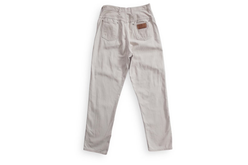 K&ouml;nnte beinhalten: Eine hellbeige Jeanshose mit einem braunen Leder-Patch auf der Ges&auml;&szlig;tasche.